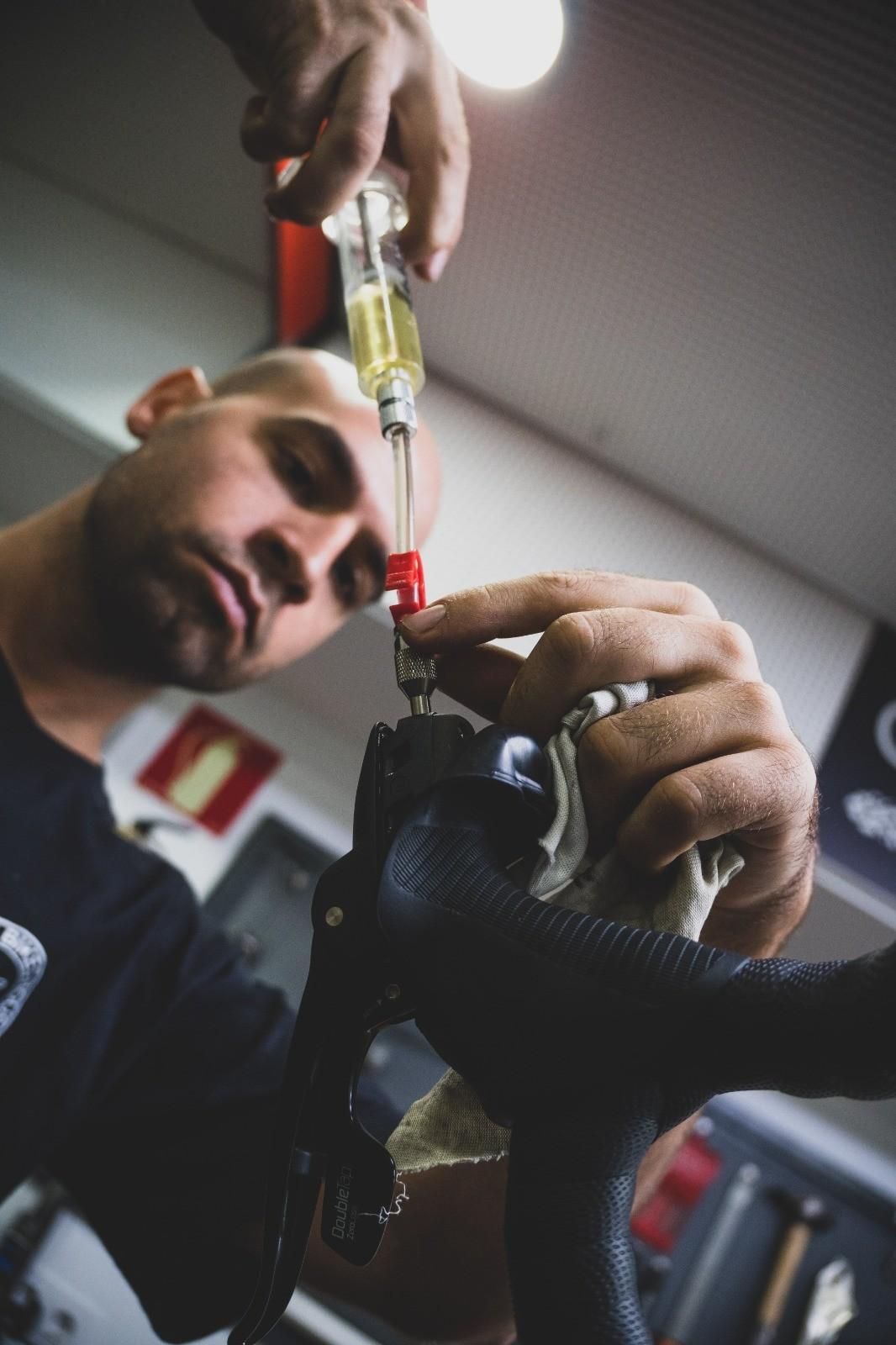 Mecánico utilizando una jeringa para extraer líquido de un componente del automóvil en un taller mecánico.