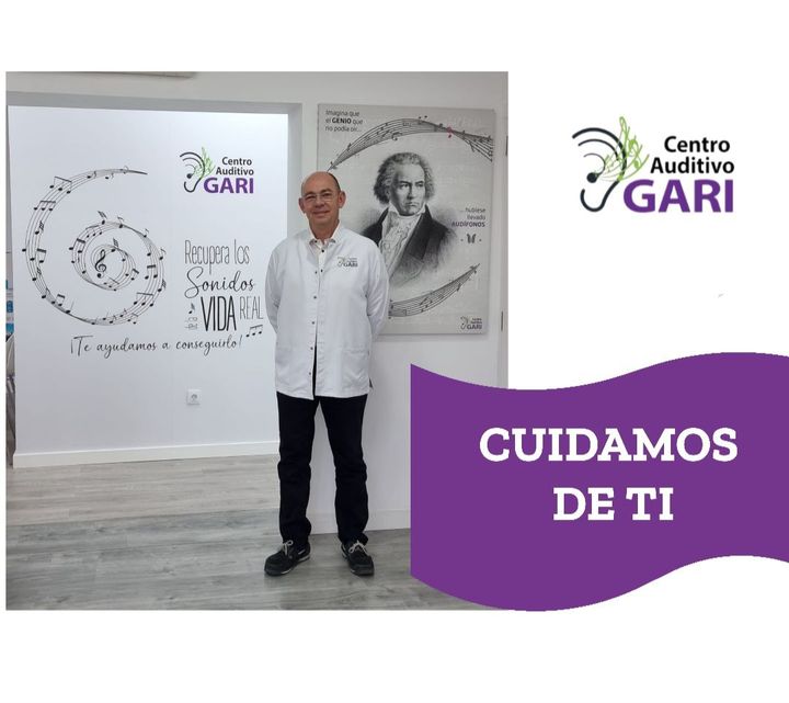 Un hombre está parado frente a un cartel que dice centro auditivo gari