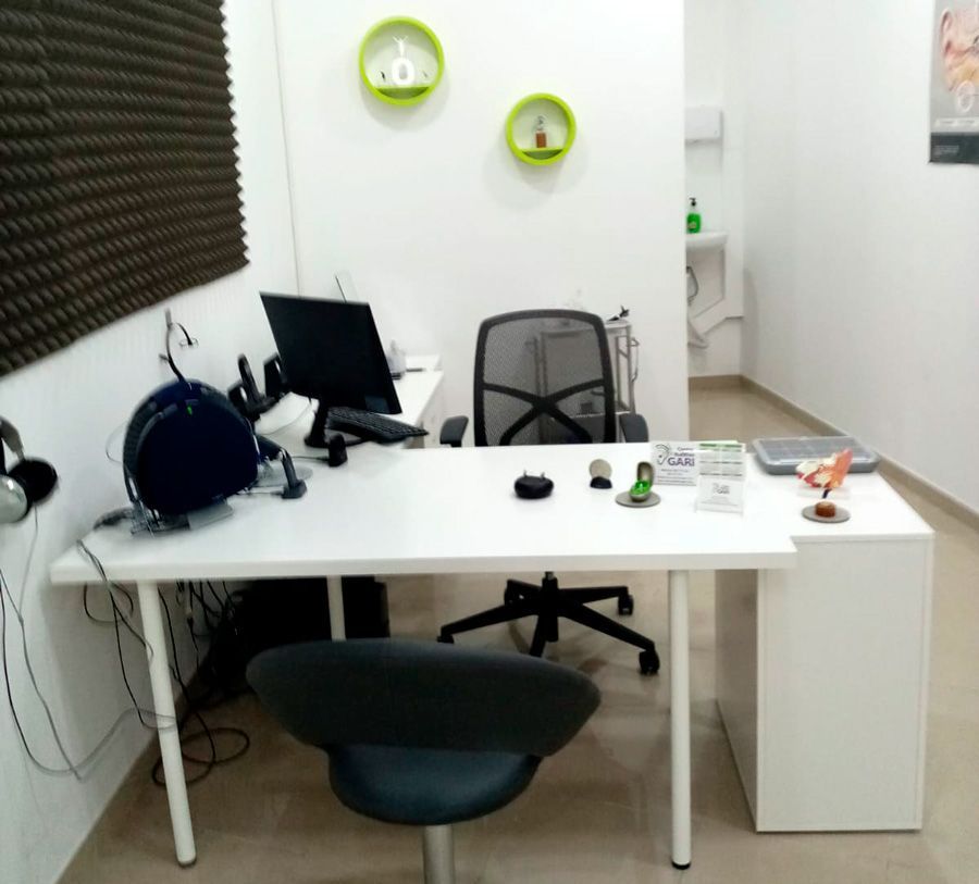 Un escritorio blanco con una silla y una computadora encima.