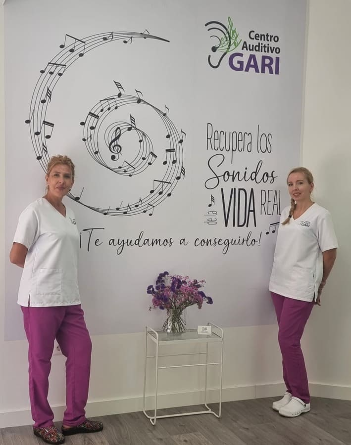 Dos mujeres paradas frente a una pared que dice centro auditivo gari