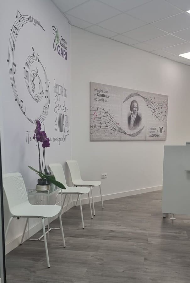 Una sala de espera con sillas y un cuadro en la pared.