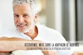 Un hombre con cabello gris y barba sonríe mientras está sentado en un sofá.