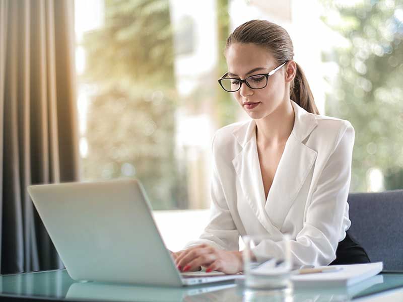Una mujer está sentada en un escritorio utilizando una computadora portátil.