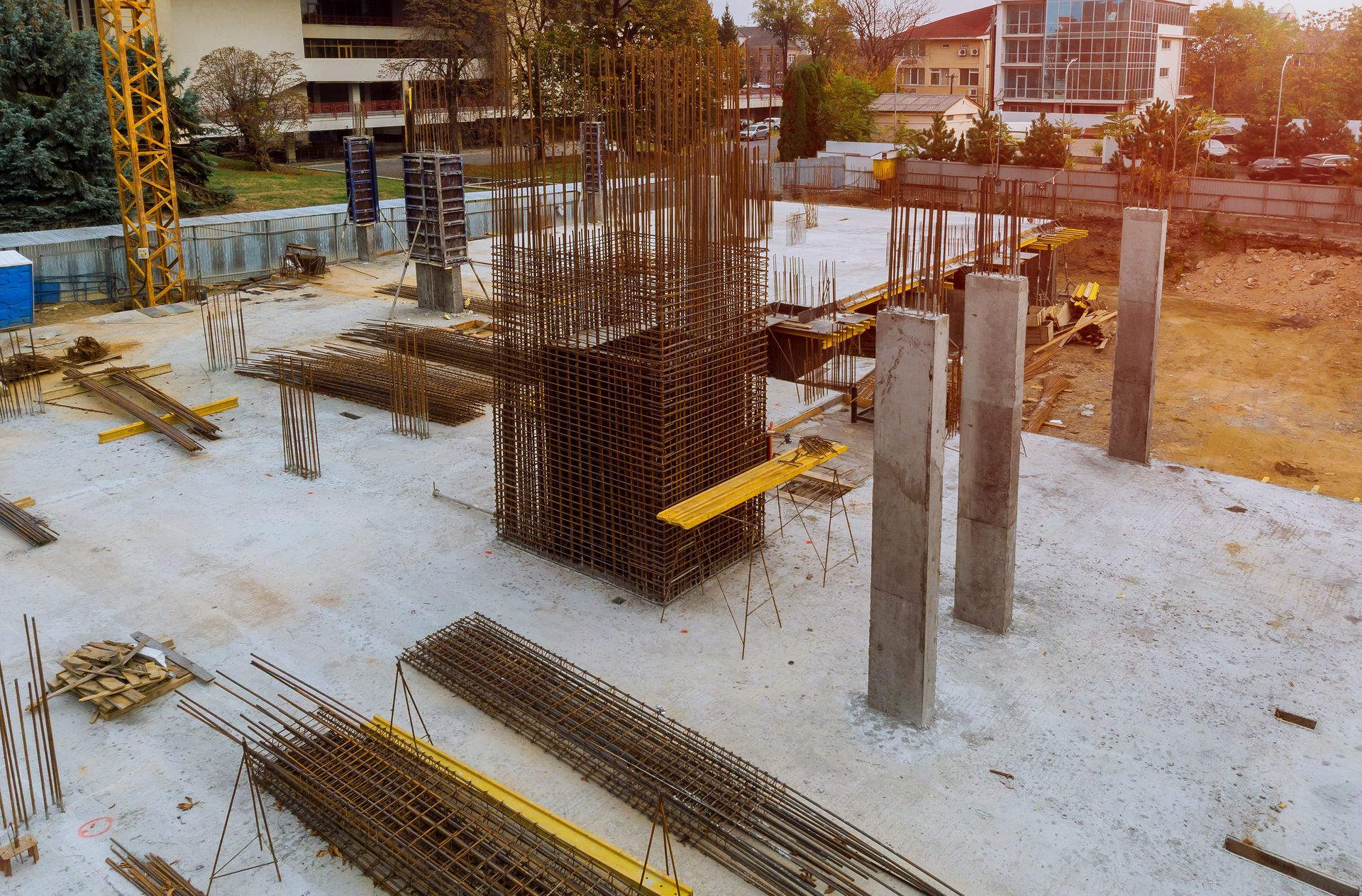 Un sitio de construcción con muchas barras de acero y una grúa al fondo.