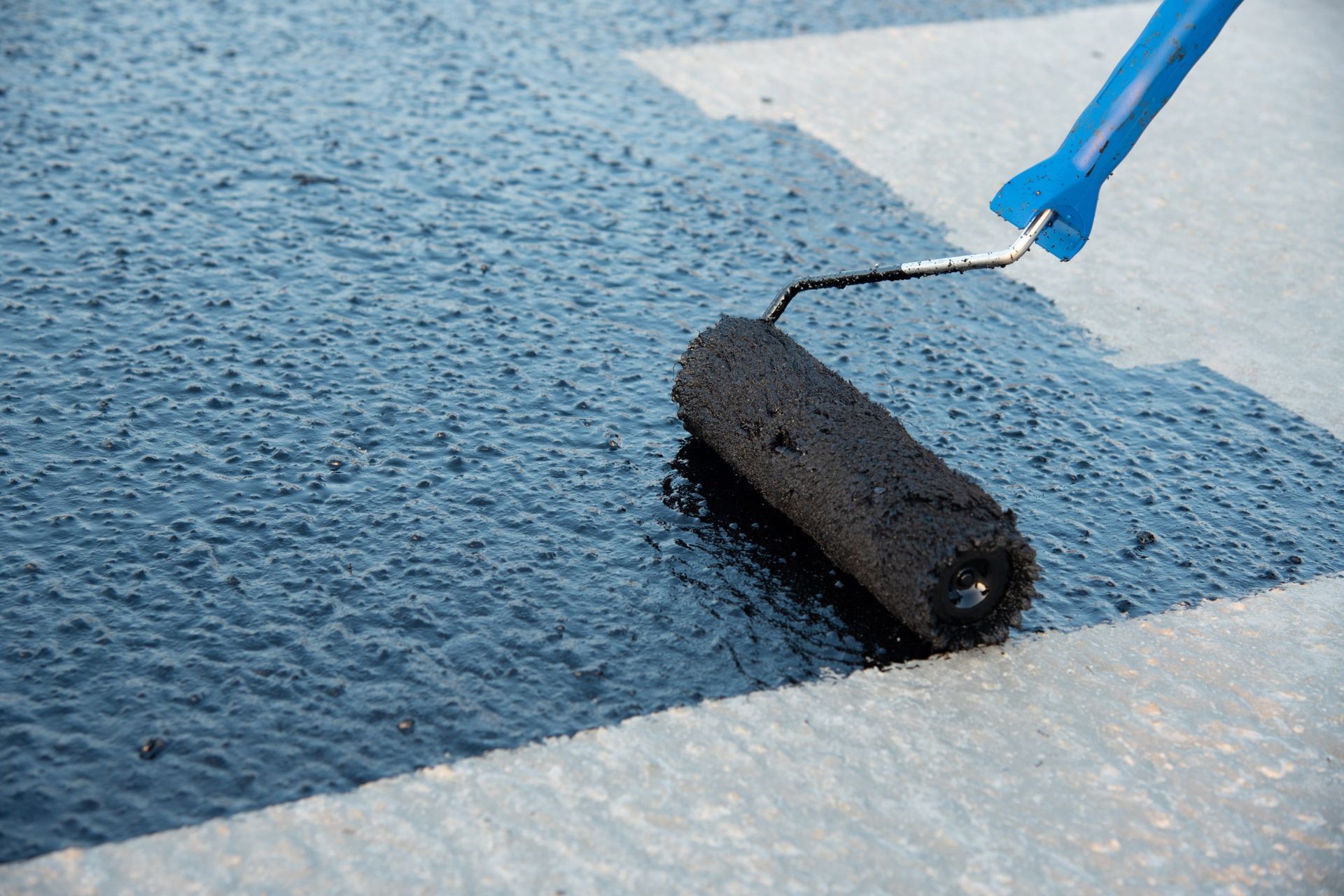 Una persona está pintando una carretera con un rodillo.