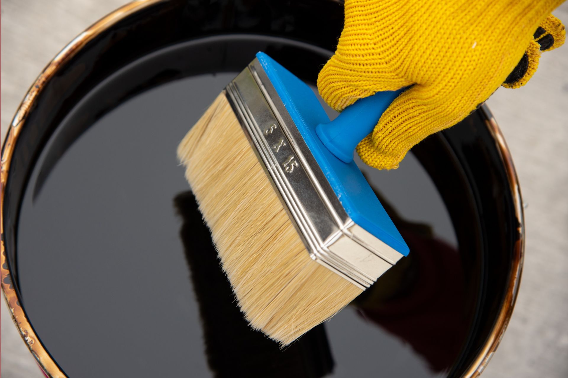 Una persona sostiene un cepillo sobre un balde de líquido negro.