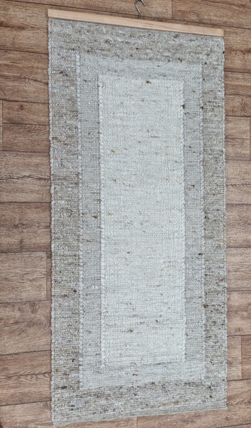 An einer Holzwand hängt ein Teppich.