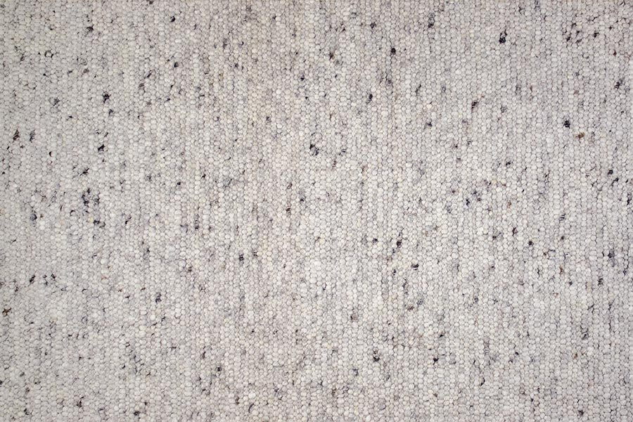 Eine Nahaufnahme eines weißen Teppichs mit schwarzen Flecken.