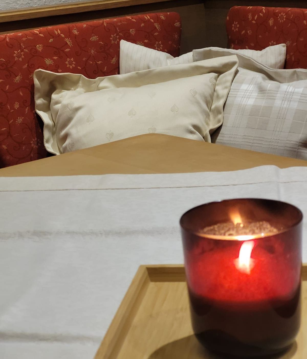 Eine brennende Kerze steht auf einem Tablett vor einem Bett