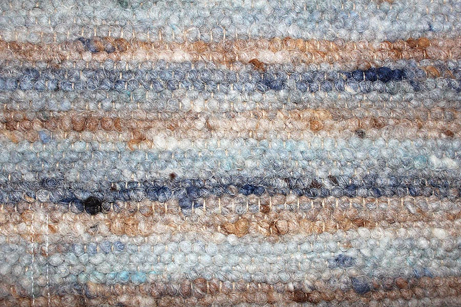 Eine Nahaufnahme eines blau-braunen Teppichs mit Streifenmuster.