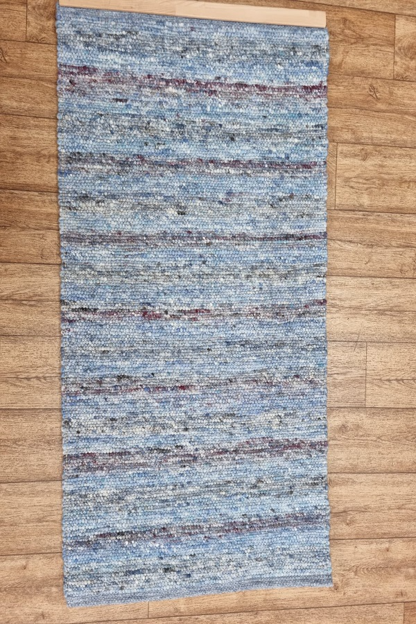 Auf einem Holzboden liegt ein blauer Teppich.