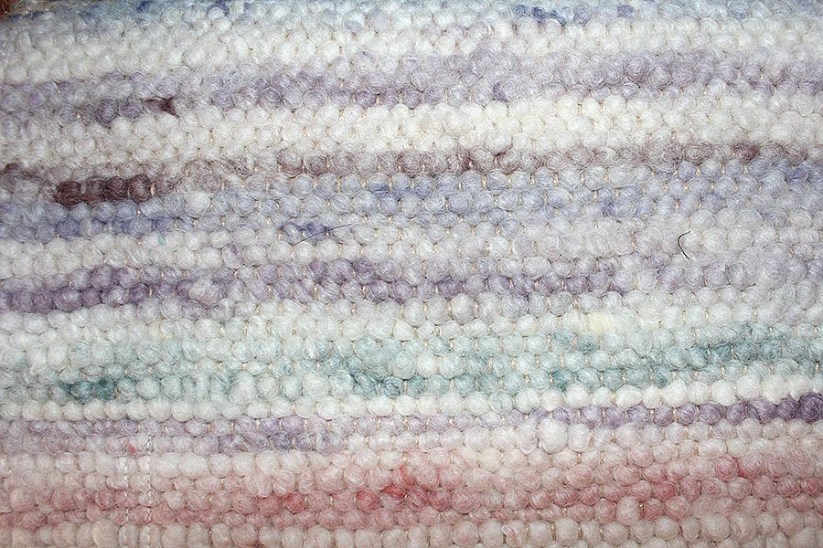 Eine Nahaufnahme eines Strickstoffes in einem Regenbogen von Farben.