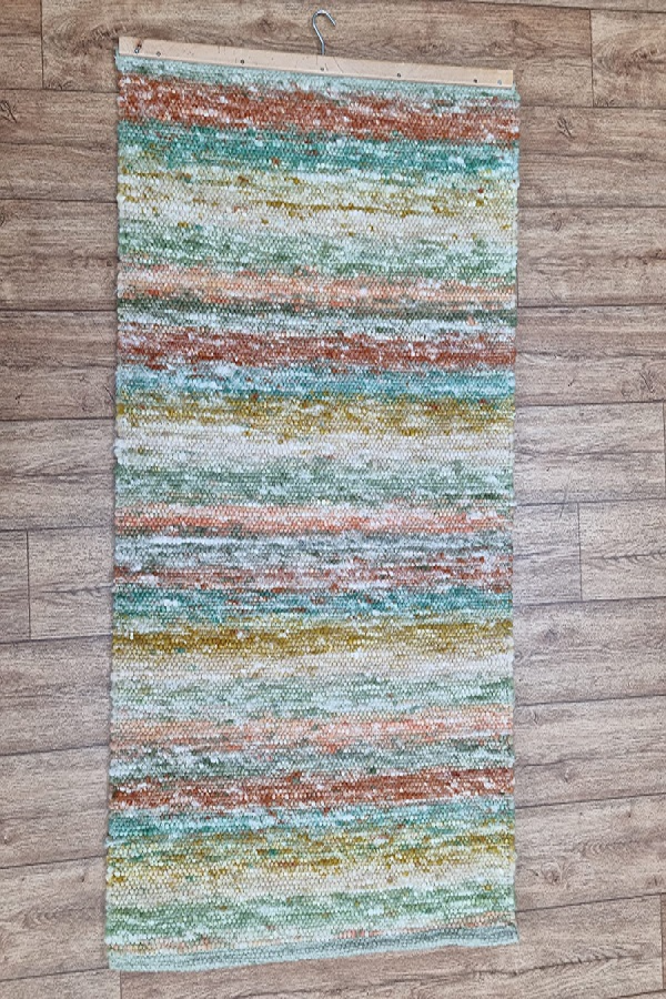 An einer Holzwand hängt ein bunter Teppich.