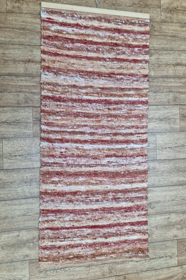 Auf einem Holzboden liegt ein rot-weiß gestreifter Teppich.