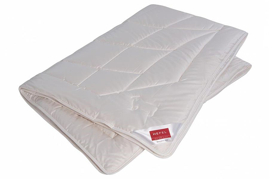 Eine weiße Bettdecke liegt auf einem Bett vor einem weißen Hintergrund.