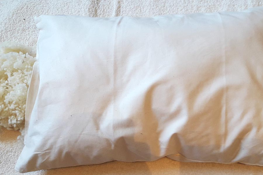 Auf einem Bett liegt ein weißes Kissen auf einem weißen Handtuch.