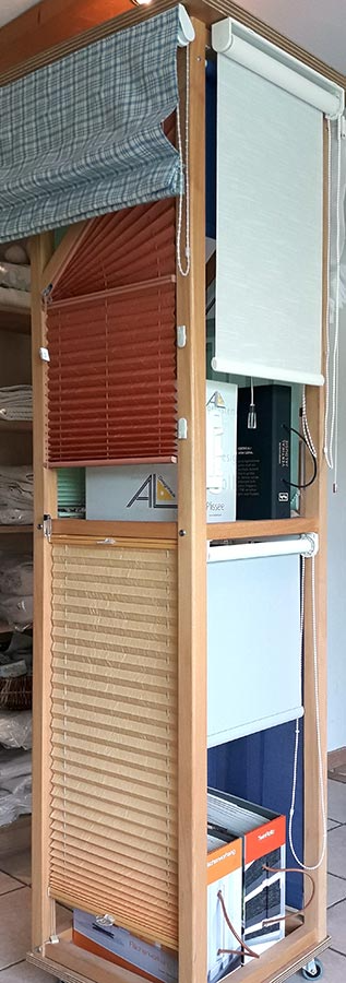 Eine Ausstellung unterschiedlicher Jalousietypen auf einem Holzständer.