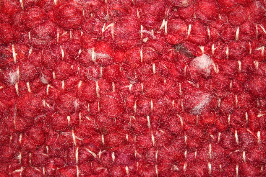 Eine Nahaufnahme eines roten Strickstoffes mit weißen Nähten.