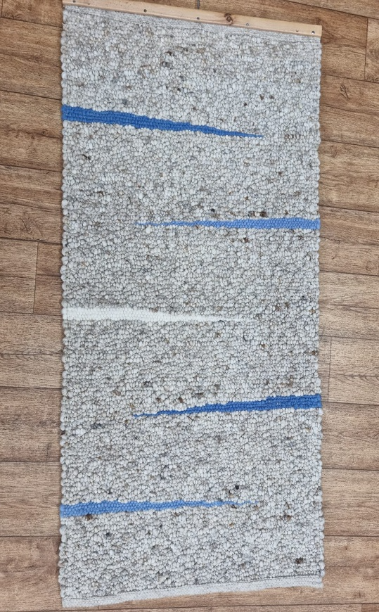 Auf einem Holzboden liegt ein grauer Teppich mit blauen Streifen.