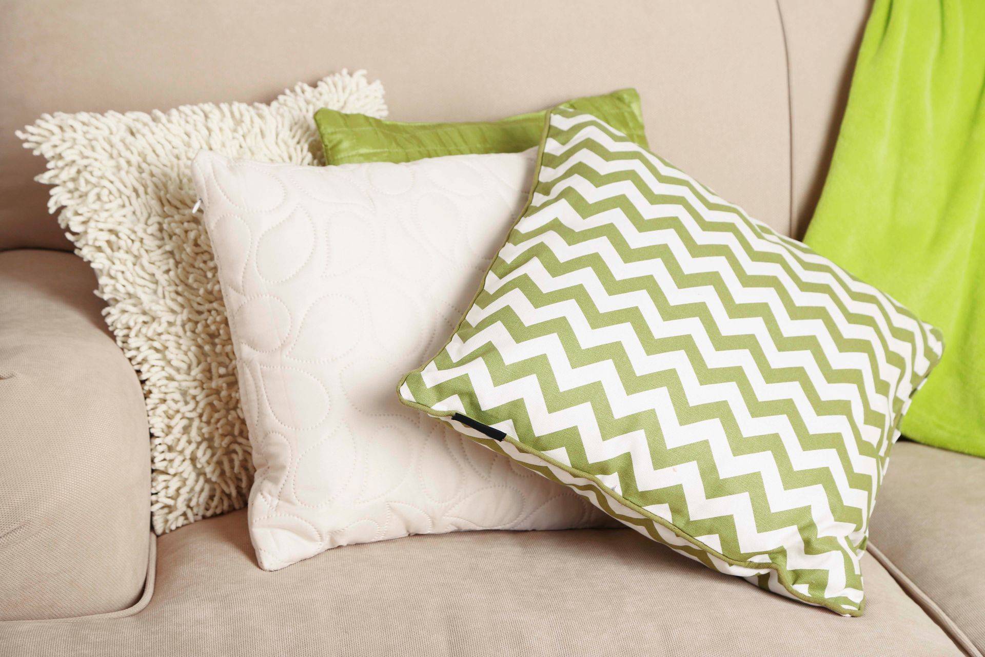 Eine Couch mit grünen und weißen Kissen darauf.