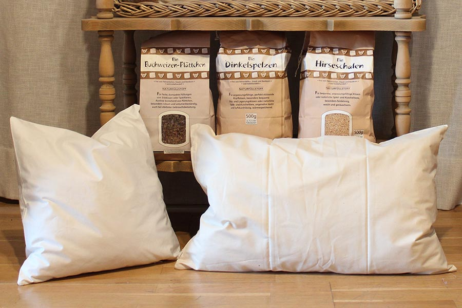 Drei weiße Kissen liegen auf einem Holzboden