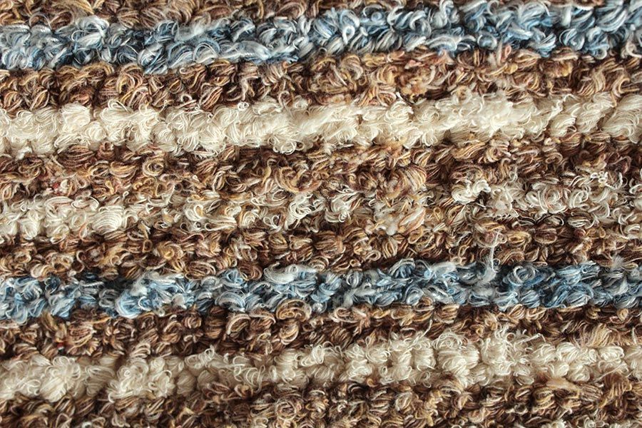 Eine Nahaufnahme eines braun und blau gestreiften Teppichs.