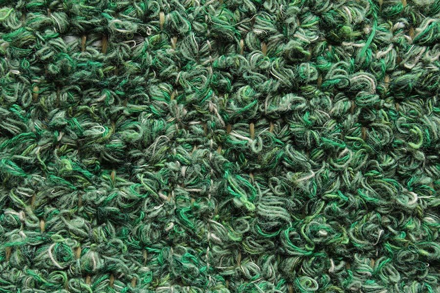 Eine Nahaufnahme der Struktur eines grünen Teppichs.