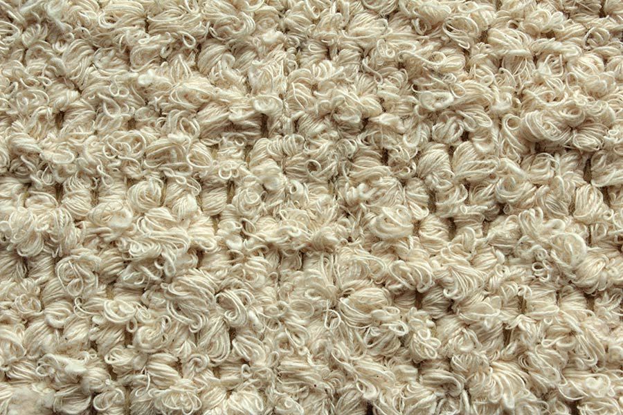 Eine Nahaufnahme der Struktur eines beigen Teppichs.