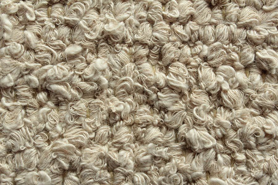 Eine Nahaufnahme eines beigen Teppichs mit Wirbelmuster.