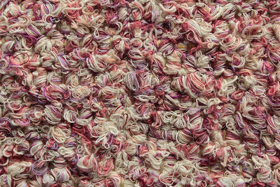 Eine Nahaufnahme einer rosa-weißen Teppichstruktur.