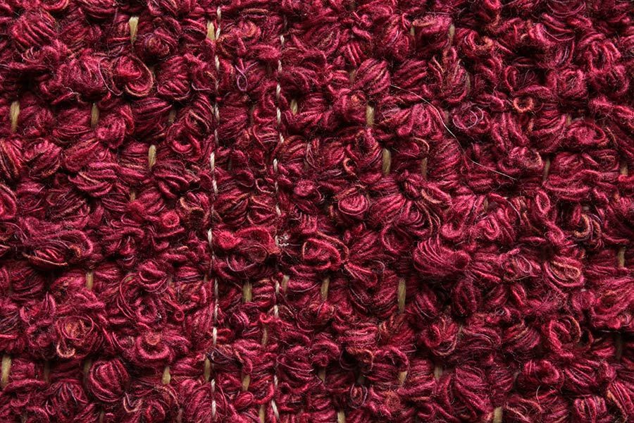Eine Nahaufnahme der Textur eines roten Teppichs.