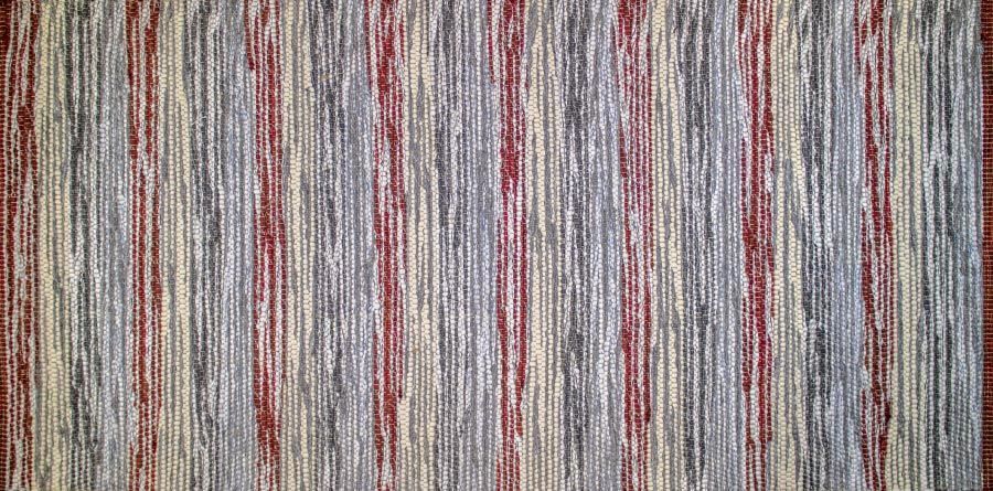 Eine Nahaufnahme eines gestreiften Teppichs mit rotem Rand.