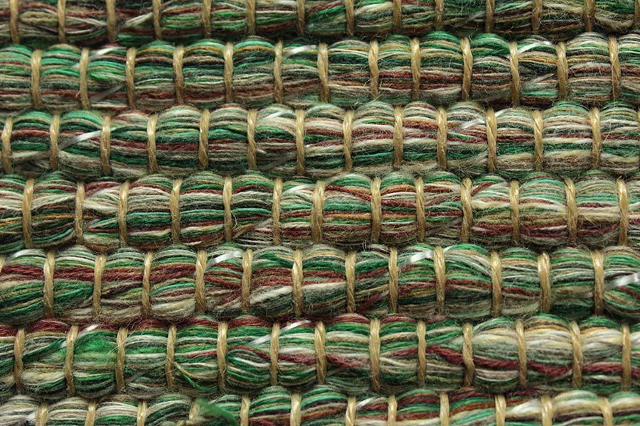 Eine Nahaufnahme eines grün-braunen Teppichs mit Streifenmuster.