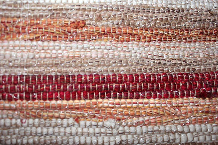 Eine Nahaufnahme eines gewebten Teppichs mit einem roten Streifen an der Unterseite.