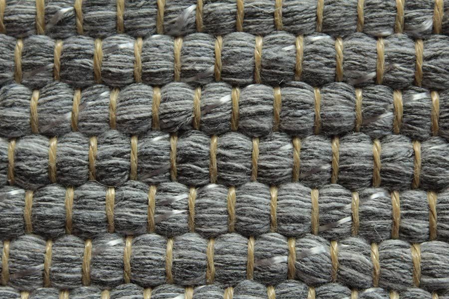 Eine Nahaufnahme eines grauen Teppichs mit braunem Rand.