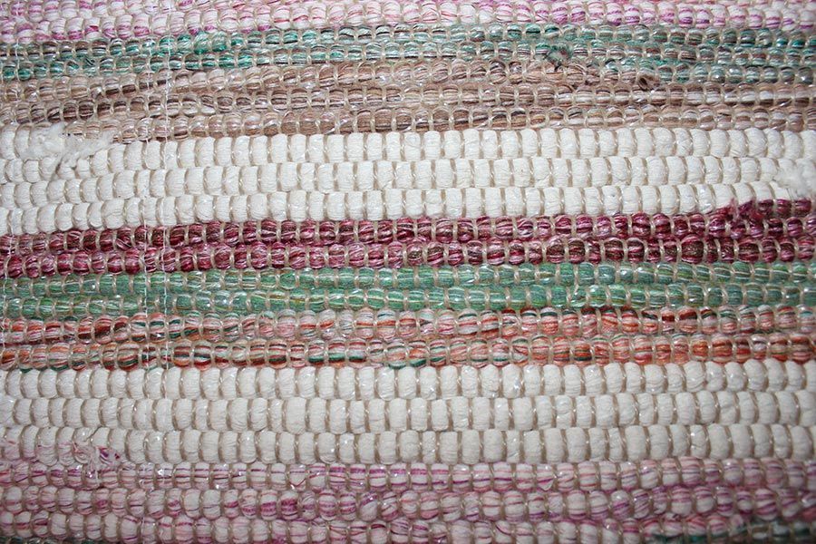 Eine Nahaufnahme eines Teppichs mit rosa, weißen und grünen Streifen.