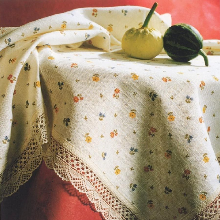 Eine Tischdecke mit Blumen und Spitzenbesatz liegt auf einem Tisch