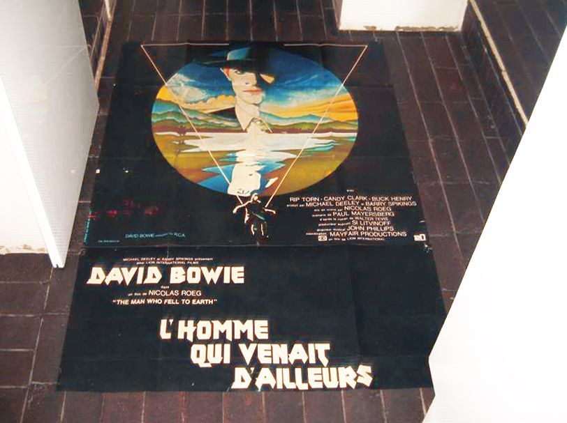 Deux affiches de film vintage pour L'Homme qui venait d'ailleurs avec David Bowie, posées sur un sol carrelé.