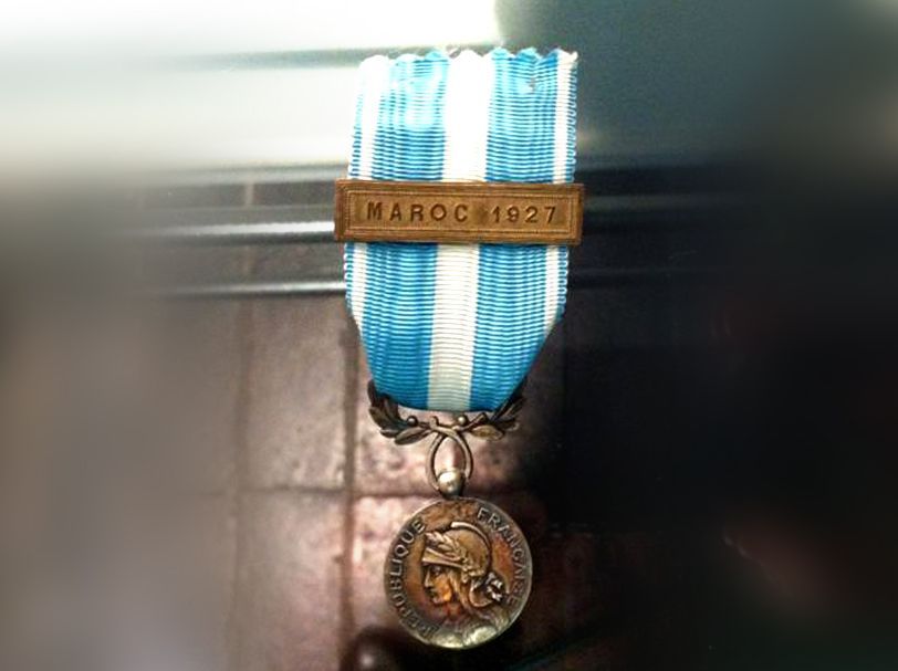 Médaille coloniale française avec un ruban rayé bleu et blanc et une barrette en bronze portant l'inscription « MAROC 1922 ».