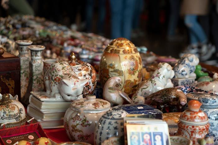 Gros plan sur des objets décoratifs en céramique vintage et de petits bibelots ornementaux disposés sur une table encombrée dans un marché.