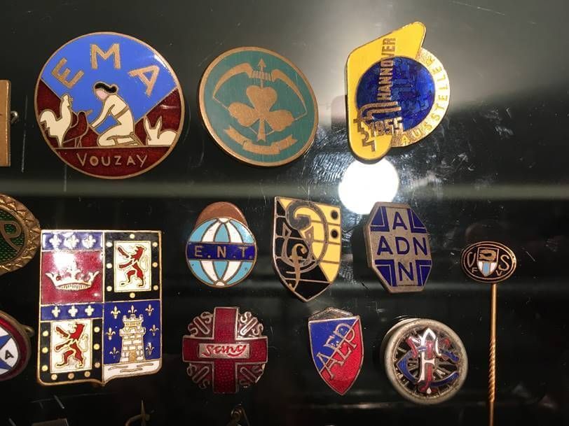 Une collection de pins vintage en émail, disposés sur un présentoir sombre.