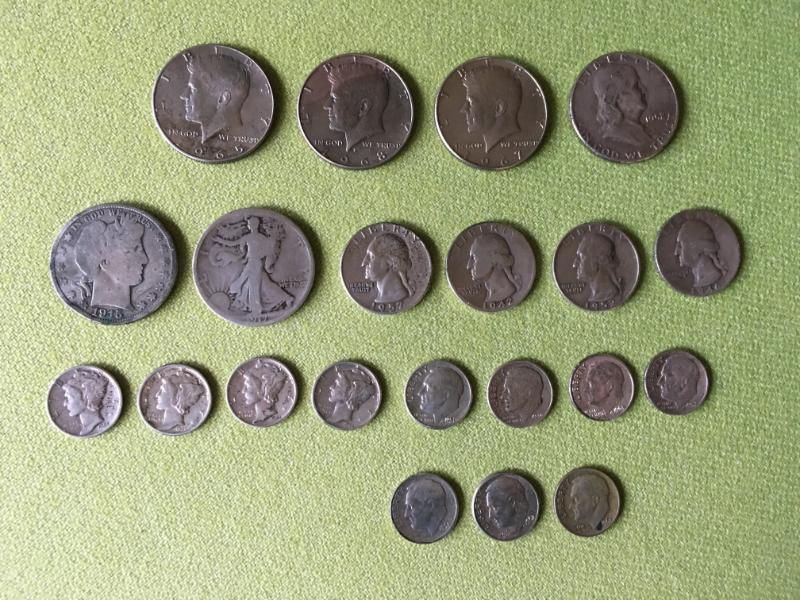 Une collection de pièces de monnaie américaines anciennes assorties, disposées en quatre rangées sur une surface verte texturée.