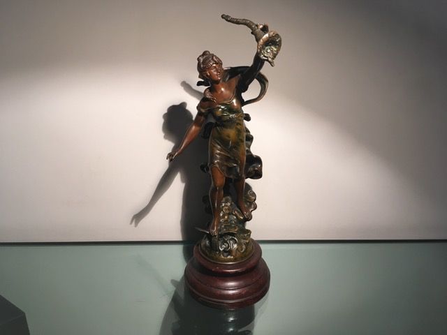 Sculpture en bronze représentant un personnage brandissant une corne d'abondance, posée sur un socle circulaire en bois sombre.