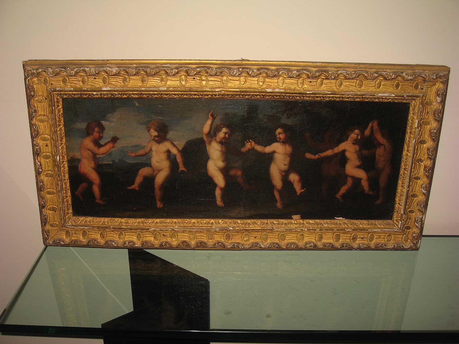 Un tableau dans un cadre doré orné représentant six chérubins dansant dans un paysage sur fond sombre.