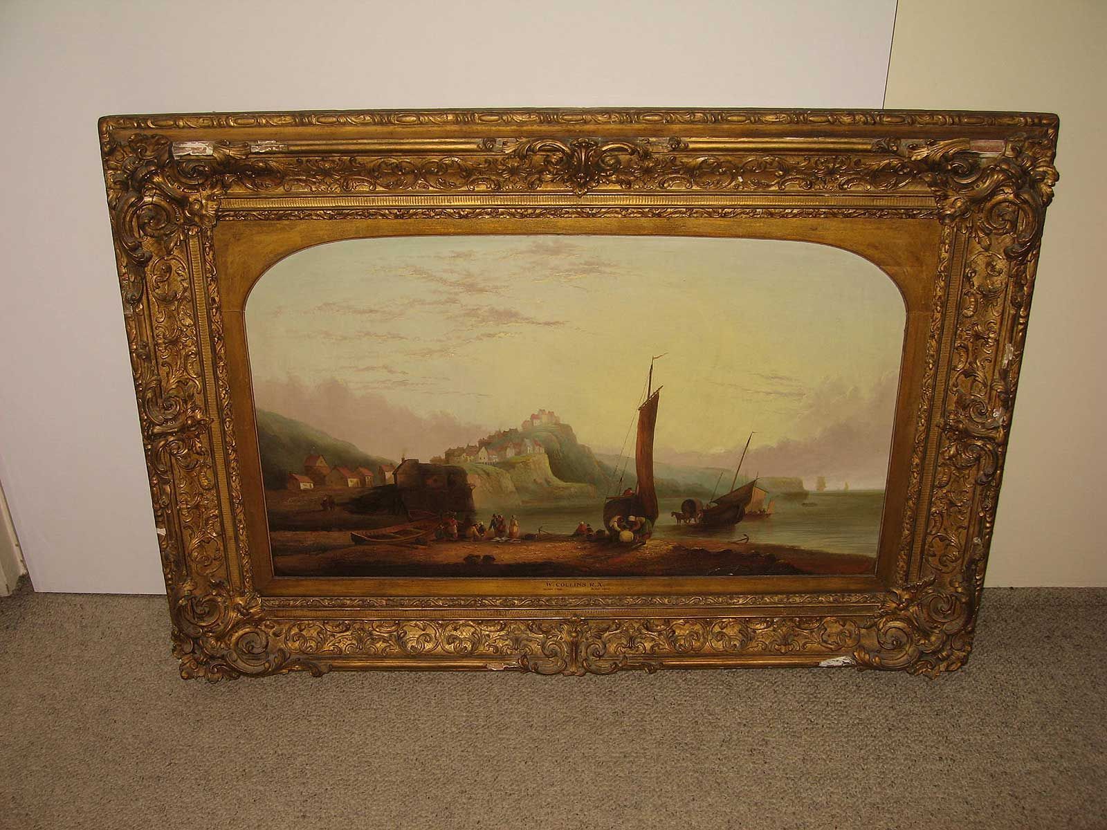 Une peinture à l'huile représentant un paysage côtier avec des bateaux, encadrée dans un cadre rectangulaire doré orné.