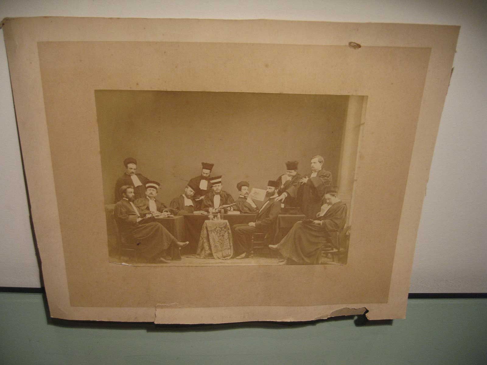 Un portrait de groupe vintage, aux tons sépia, représentant des personnes en tenue de soirée, assises et debout autour d'une table.