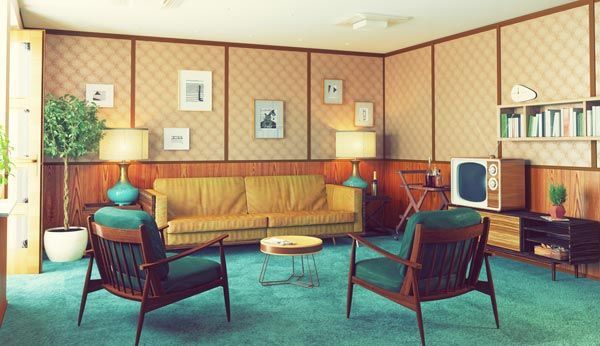 Un salon rétro de style années 1970 avec un canapé beige, deux fauteuils turquoise, une moquette verte, des murs lambrissés et une télévision vintage.