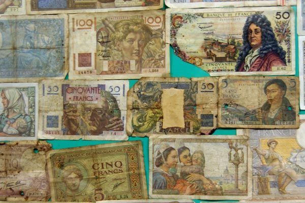 Un collage de divers billets de banque français anciens dans des tons de bleu, beige et marron, avec des portraits et des illustrations.