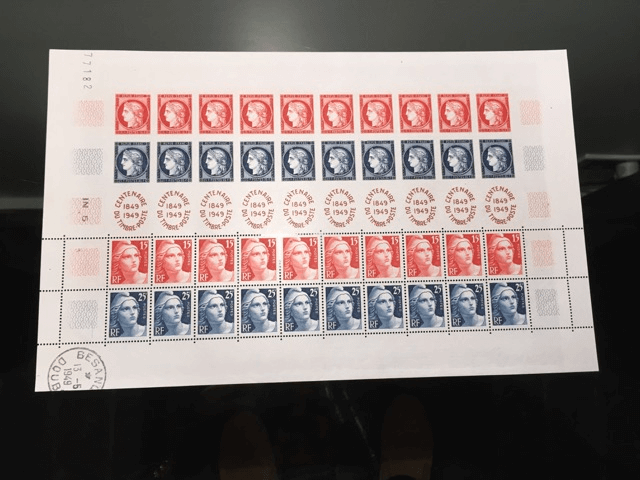 Une feuille de timbres-poste présentant cinq rangées de portraits rouges et bleus alternés, avec un cachet postal circulaire en bas.