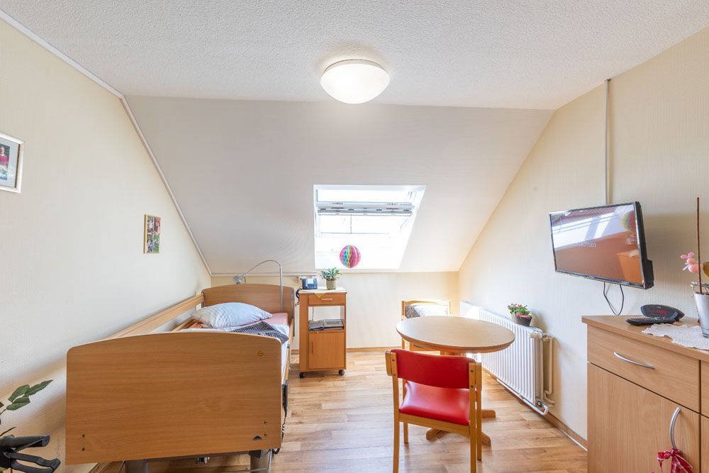 Ein Schlafzimmer mit zwei Betten, einem Tisch und einem Fernseher.